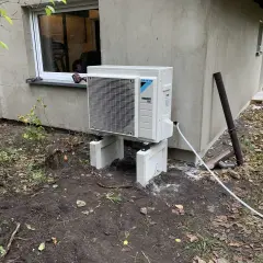 Nowoczesna pompa ciepła woda woda Daikin, zamontowana na zewnątrz budynku, gotowa do pracy.