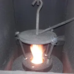 Płomień w piecu na ekogroszek. Widoczny metalowy deflektor z regulacją, który poprawia spalanie.