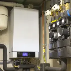 Nowoczesny piec dwufunkcyjny z panelem sterowania i grupą hydrauliczną. Widać, że kapie woda z pieca dwufunkcyjnego, co może wskazywać na problem.