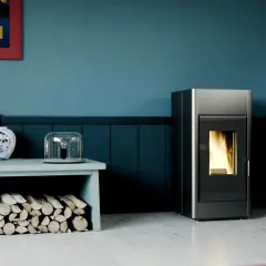 Nowoczesny kominek na pellet, płomienie tańczą w środku. Obok stos drewna i dekoracje.