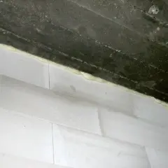 Dylatacja komina od stropu wykonana pianką montażową. Białe pustaki i ciemny strop.