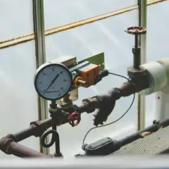 Manometr pokazuje ciśnienie w układzie zamkniętym. Rury i zawory są częścią instalacji.