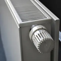 Biały grzejnik z termostatem, idealny do ogrzewania etażowego. Ustaw temperaturę na komfortowy poziom.