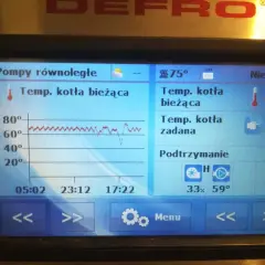 Wyświetlacz kotła Defro pokazuje temperaturę kotła bieżącą 66°C i zadaną 70°C. Widoczny jest wykres temperatury i wskaźnik podtrzymania.