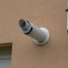 Boczny wyrzut spalin przez ścianę, zgodny z przepisami, obok wentylacji.
