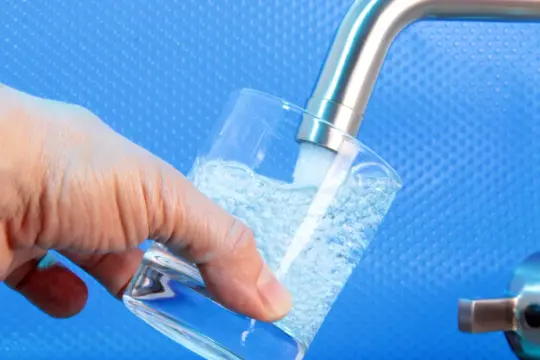 Woda z kranu nalewana do szklanki. Prawidłowa temperatura bojlera zapobiega rozwojowi legionella.