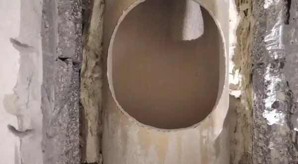 Otwór w ceramicznym kominie, przygotowany do dalszych prac. Widać izolację i fragmenty konstrukcji.