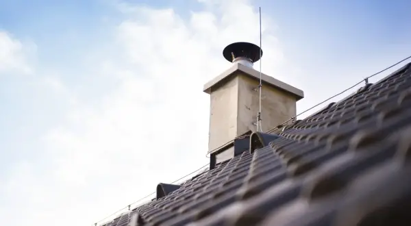 Zastanawiasz się, ile kosztuje rozbiórka komina i postawienie nowego? Na zdjęciu widać dach z kominem, który może wymagać remontu.