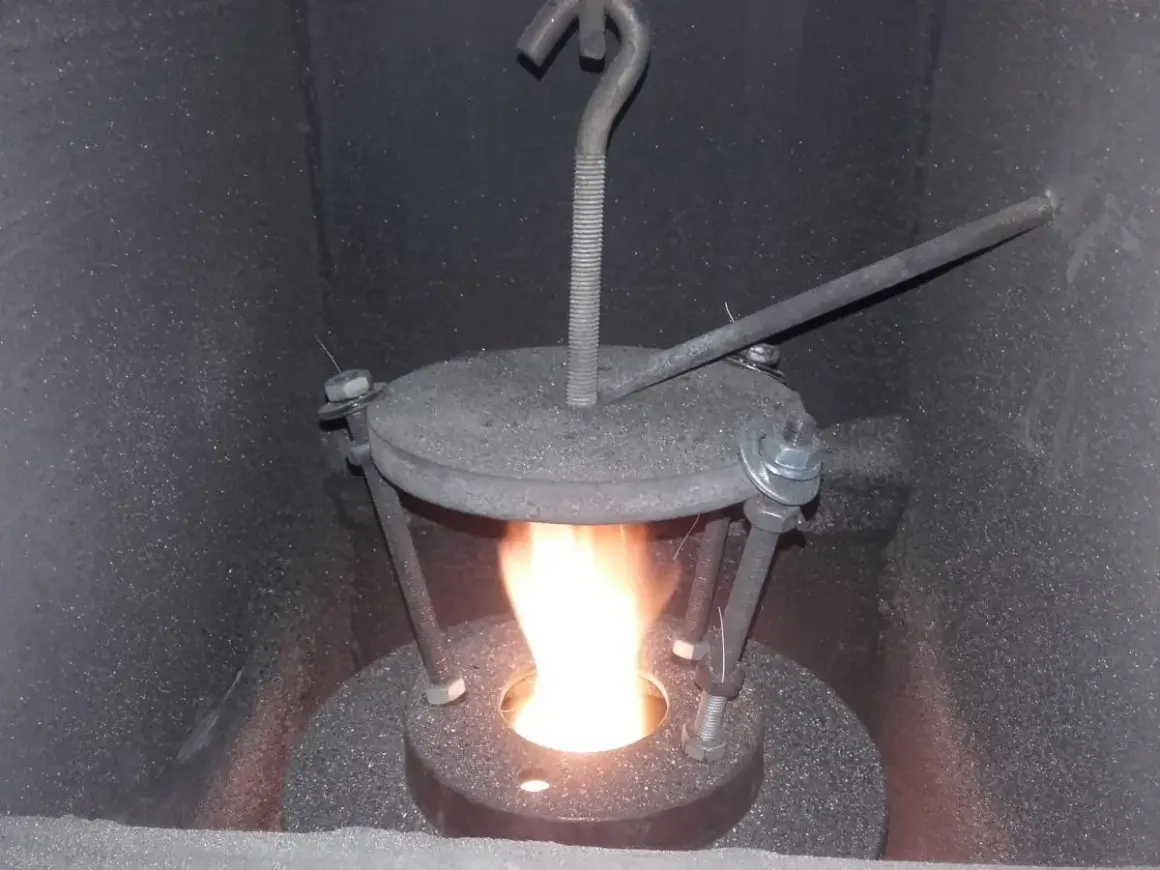 Płomień w piecu na ekogroszek. Widoczny metalowy deflektor z regulacją, który poprawia spalanie.