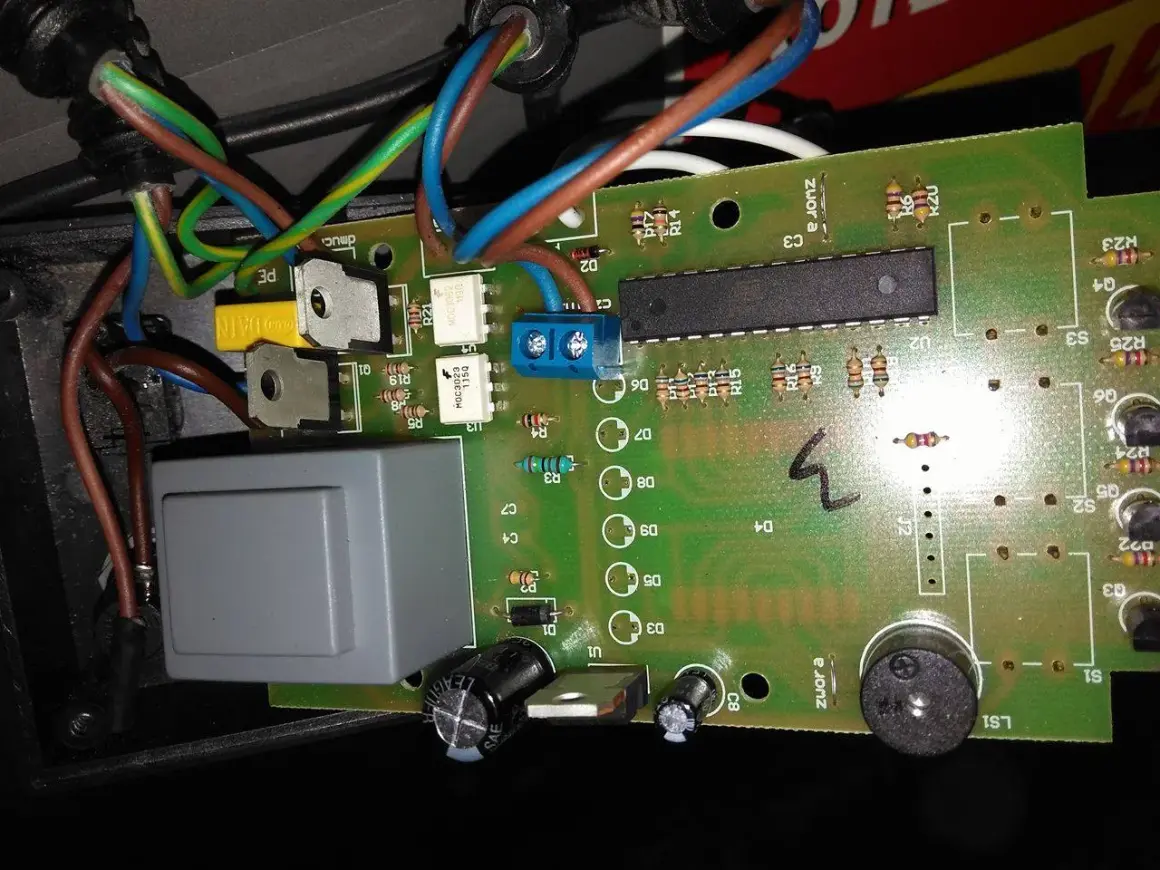 Sterownik Atos jak ustawić? Widok płytki drukowanej z elementami elektronicznymi, przewodami i przekaźnikiem.