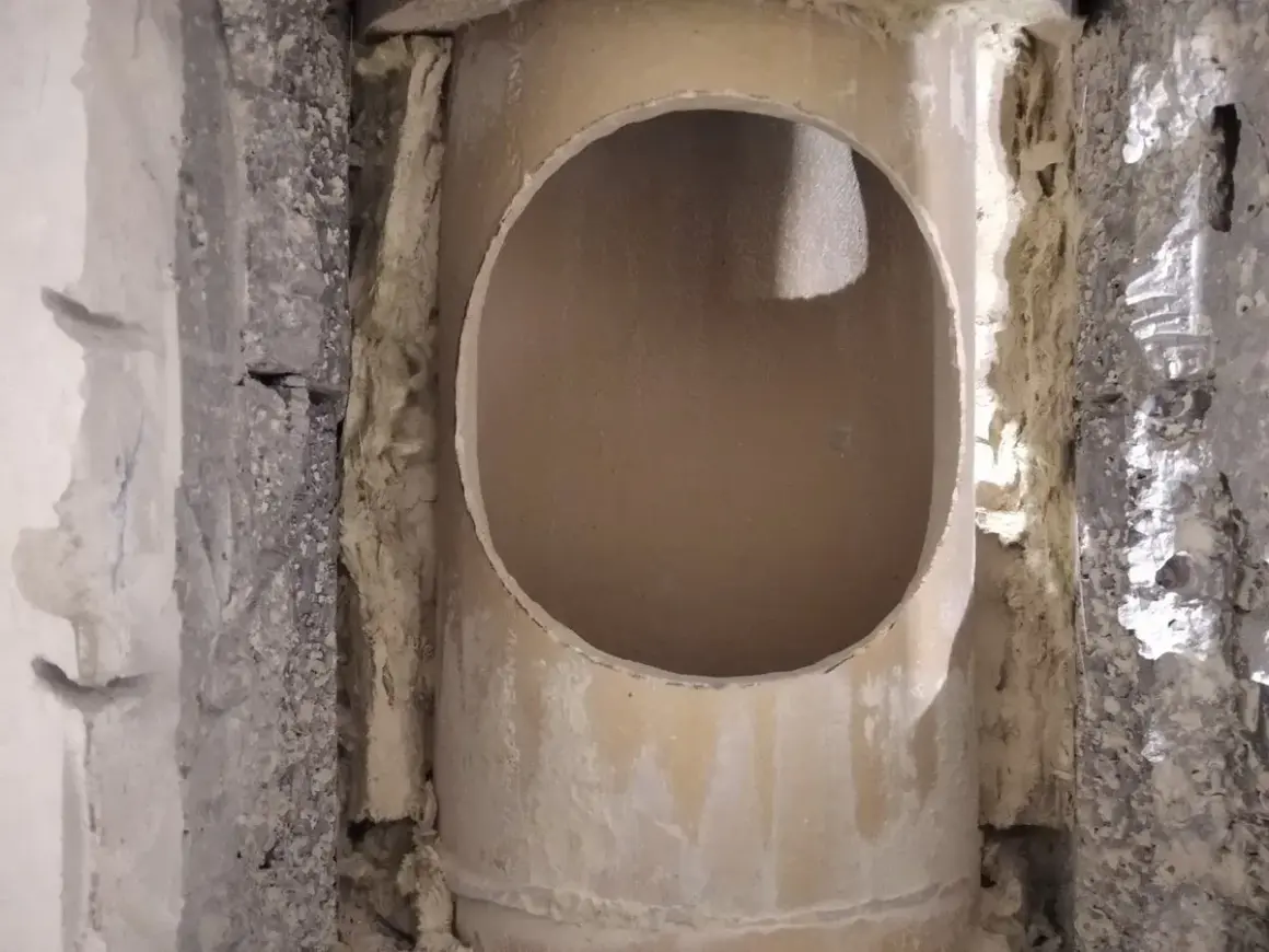 Otwór w ceramicznym kominie, przygotowany do dalszych prac. Widać izolację i fragmenty konstrukcji.