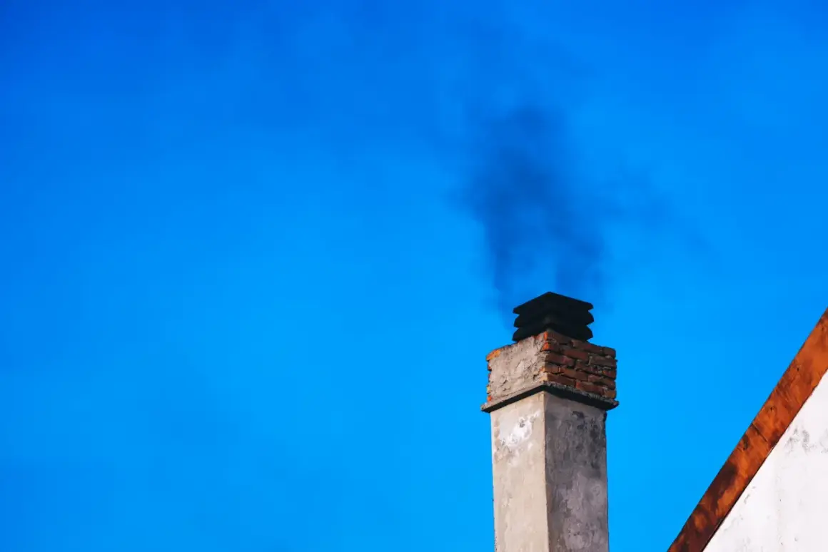 Dym z komina, być może dzięki zastosowaniu filtra kominowego zamiast wymiany pieca, unosi się na tle błękitnego nieba.