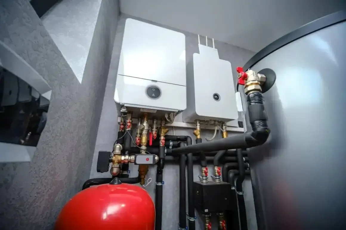 Dwa kotły gazowe z instalacją hydrauliczną, w tym czerwony zbiornik i rury odprowadzające skropliny z pieca gazowego.