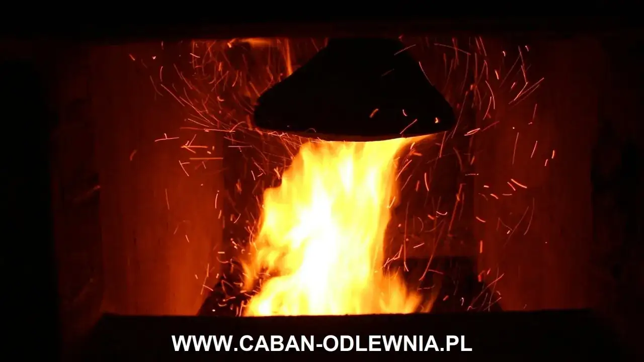Płomienie w piecu na ekogroszek, nad nimi czarny deflektor. Iskry tańczą w gorącym powietrzu.
