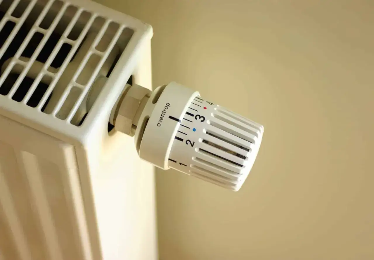 Biały kaloryfer z termostatem Oventrop, ustawionym na 2.5. Różne rodzaje kaloryferów oferują różne sposoby regulacji temperatury.